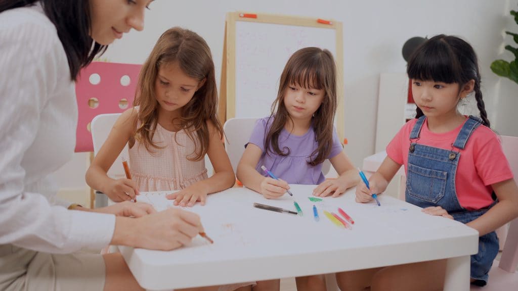 Back to school and summer course. Kindergarten teacher with children drawing and coloring.