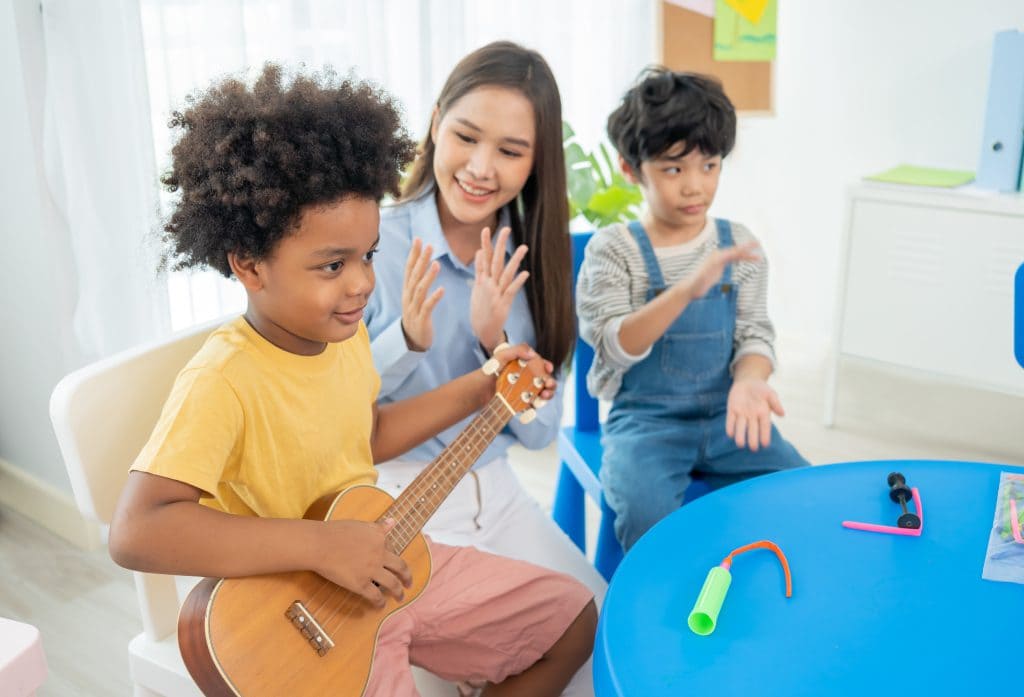 Back to school and summer course. Little children play guitar in kindergarten classroom.