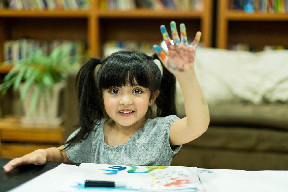 A girl showing her hand with colours on them.