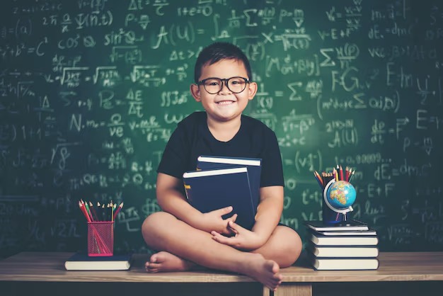 boy with books sitting near green chalkboard 1150 3844